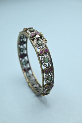 a close up of a gold ring with pink and green stones