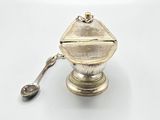 a silver teapot with a spoon on a white table