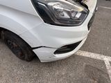 the front end of a white van with a denting dent on it