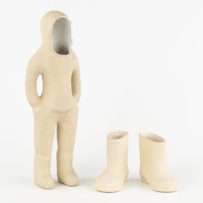 une petite statue représentant un homme debout à côté d'une paire de bottes