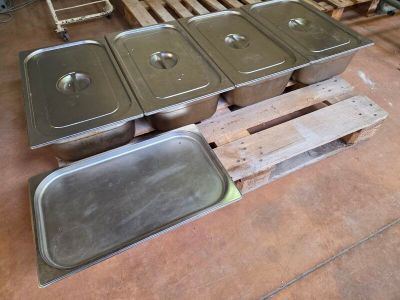 several stainless steel pans sitting on top of a pallet in a warehouse