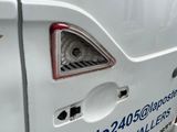 une camionnette blanche avec des inscriptions bleues, garée sur le bord de la rue