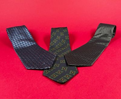 three men ' s neck ties laying on a red surface