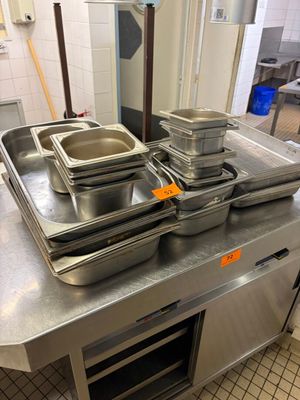 Plusieurs casseroles remplies d'aliments sont posées sur un plan de travail en inox.