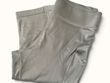 le bas d'un pantalon gris posé sur une surface blanche