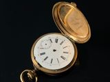 a gold pocket watch with roman numerals on it