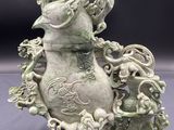 un vase vert orné d'un dragon, posé sur une table