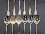 six silver spoons are lined up in a row on a black surface