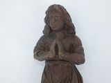 a wooden statue of a woman holding her hands together