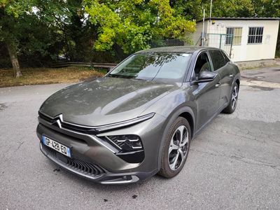 La voiture grise est garée sur le parking à côté d'une maison.