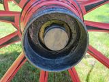 a close up of a red wagon wheel on the grass