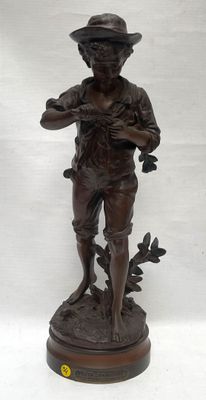 bronze statue of a boy with a hat and holding a bird