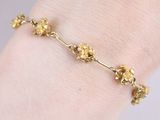 a close up of a person wearing a gold bracelet with flowers on it