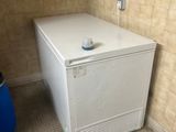 un petit réfrigérateur blanc dans un coin de la salle de bains