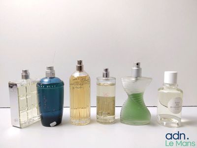 several bottles of perfume are lined up on a white surface