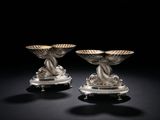 une paire de bougeoirs en argent sur des socles, sur fond noir