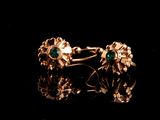 un gros plan sur une paire de boucles d'oreilles en or ornées d'émeraudes