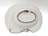 a white plate with a gold rim on a stand