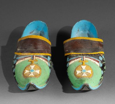 two pairs of clogs with decorative designs on them on a gray surface