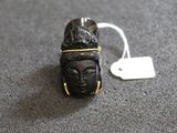 une petite statuette noire représentant Bouddha, à laquelle est attachée une étiquette