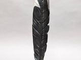a black and white feather sitting on a white stand