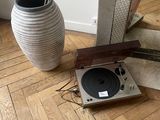 a record player sitting on the floor next to a vase
