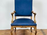 une chaise bleue posée sur un parquet, près d'un mur blanc