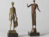 deux statues en bronze représentant une femme et un homme debout l'un à côté de l'autre