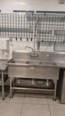 une grande cuisine en inox équipée d'un évier et d'un lave-vaisselle