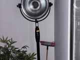 a fan that is on a stand next to a potted plant