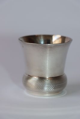 une tasse en argent posée sur une surface blanche