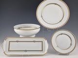 quatre pièces de vaisselle blanche et dorée, comprenant un bol, une assiette et un plat de service