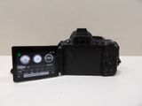 a black camera sitting on a white table next to a cell phone