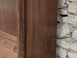 a wooden dresser sitting against a wall with a stone wall behind it
