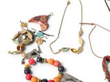 many different necklaces and bracelets on a white surface