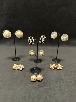 six pairs of earrings and a pair of earrings on a stand