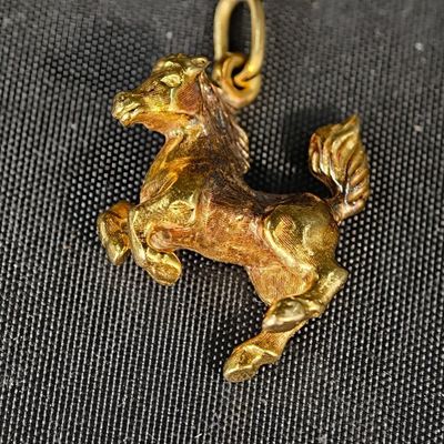 un pendentif en forme de cheval doré, fixé sur un tissu noir