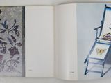 an open book with a picture of a chair and a painting on it
