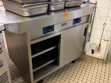 Plusieurs casseroles sont empilées sur un plan de travail en acier inoxydable dans une cuisine professionnelle.