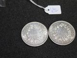 two silver coins sitting next to each other on a black surface
