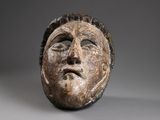 gros plan d'un masque en bois sur une surface grise