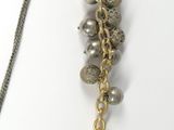 a silver and gold necklace with bells hanging from it