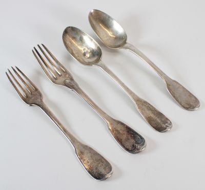 cinq cuillères en argent et une fourchette posées sur un plateau blanc