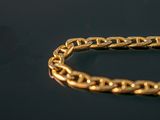 a close up of a gold chain bracelet on a black surface