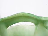 a green vase with a curved handle on a table