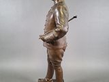 bronze statue of a man with a hat and cane standing on a wooden base