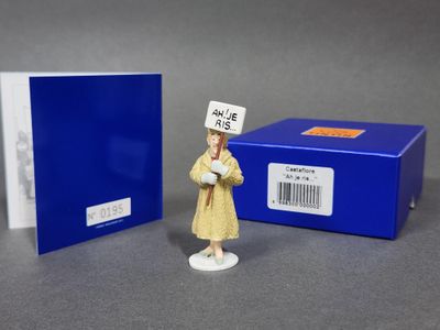 une petite figurine représentant une femme en robe jaune et une boîte bleue