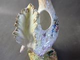 a small vase with a bird on it on a table