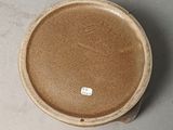 a brown bowl sitting on a table with a tag on it