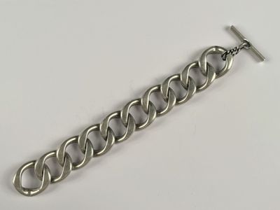 gros plan d'un bracelet en chaîne en argent sur une surface blanche